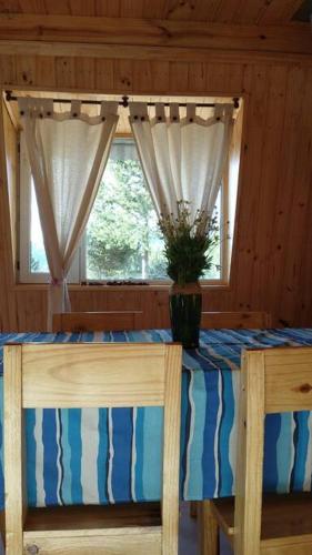 a table with two chairs and a vase of flowers on it at La Torre del Rio in Lago Meliquina
