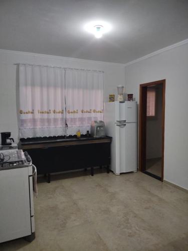 a kitchen with a white refrigerator and a window at Aconchego Cuesta de Botucatu Ninho verde 2 in Pardinho