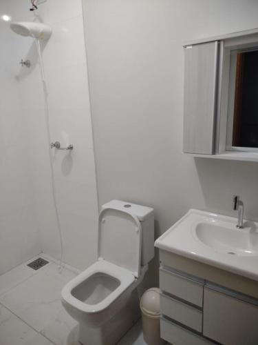 a white bathroom with a toilet and a sink at Aconchego Cuesta de Botucatu Ninho verde 2 in Pardinho