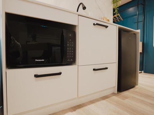 a kitchen with white cabinets with a microwave at Apê Paulista Bela Cintra in Sao Paulo