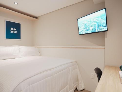 a bedroom with a bed and a flat screen tv on the wall at Apê Paulista Bela Cintra in Sao Paulo
