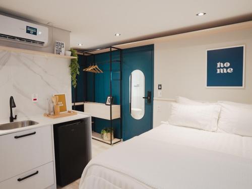 um quarto com uma cama branca e uma porta azul em Apê Paulista Bela Cintra em São Paulo