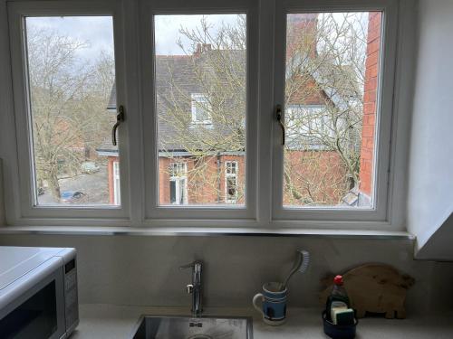 three windows in a kitchen with a sink at Peaceful flat in The Park in Nottingham