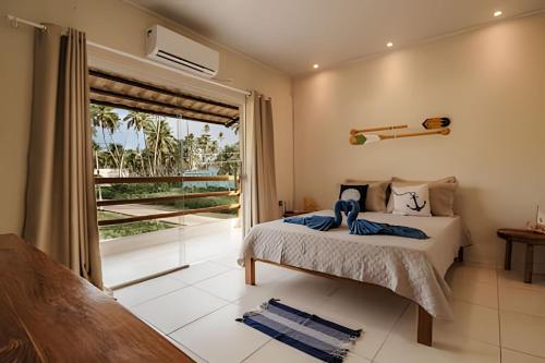 a bedroom with a bed and a large window at Flats Japaratinga - a 200m da praia com varanda in Japaratinga