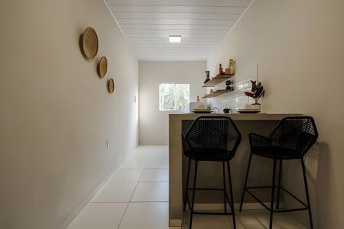 a kitchen with two chairs and a counter in a room at Flats Japaratinga - a 200m da praia com varanda in Japaratinga