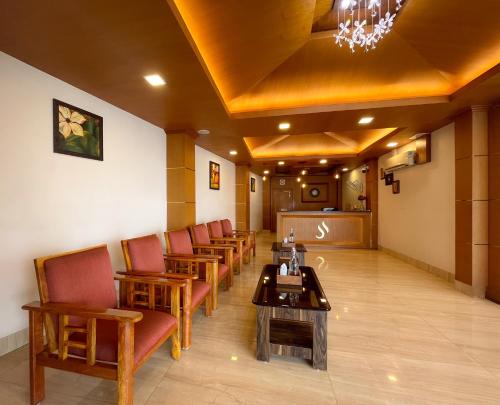 una sala de espera con una fila de sillas y una mesa en Shree Residency en Erode