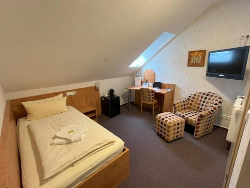 a room with a bed and a chair and a desk at Hotel am Steinertsee - Kassel-Ost in Kaufungen