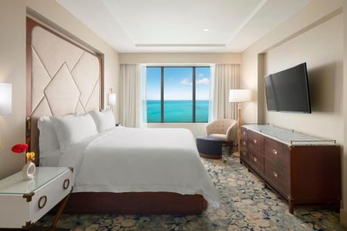 een slaapkamer met een groot bed en een groot raam bij The Residences at The St. Regis Bermuda in Saint George