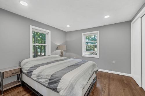 a white bedroom with a bed and two windows at Waterfront Sun-Drenched Hermit Lake Retreat! in Sanbornton