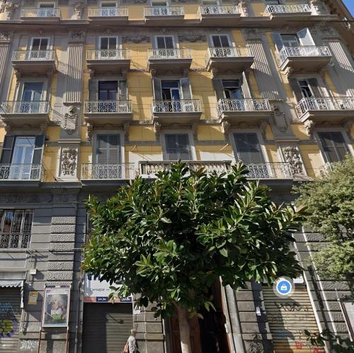 un edificio amarillo con un árbol delante de él en Napolidays Downtown Naples By Dimorra en Nápoles