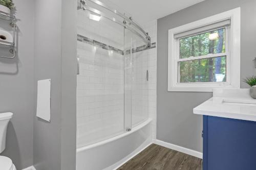 a white bathroom with a shower and a sink at Waterfront Sun-Drenched Hermit Lake Retreat! in Sanbornton