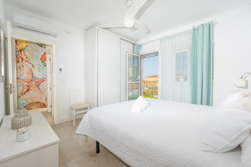 Un dormitorio blanco con una cama grande y una ventana en Precioso chalet a pie de playa, en Punta Umbría