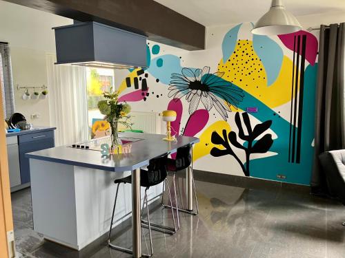 eine Küche mit einem Tisch und einer farbenfrohen Wand in der Unterkunft La Maison des bois 