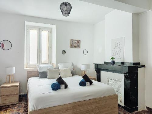 - une chambre blanche avec un lit et une cheminée dans l'établissement Le Barès, à Carcassonne