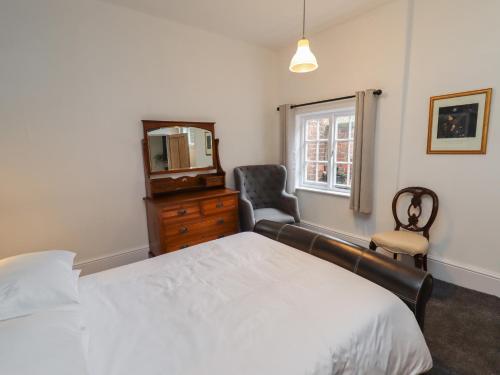 a bedroom with a bed and a mirror and a chair at The Old Sorting Office in Hawarden