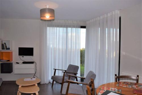 un salon avec une table, des chaises et une télévision dans l'établissement Maison neuve de plain-pied avec WIFI classée 3 étoiles à Trégastel Ref 465, à Trégastel