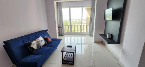 a living room with a blue couch and a table at SD Zanita Heights Sea Facing Serviced Apartments in Vasco Da Gama