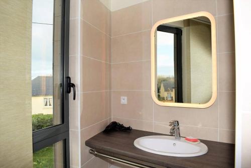 ein Bad mit einem Waschbecken und einem Spiegel in der Unterkunft Maison neuve de plain-pied avec WIFI classée 3 étoiles à Trégastel Ref 466 in Trégastel