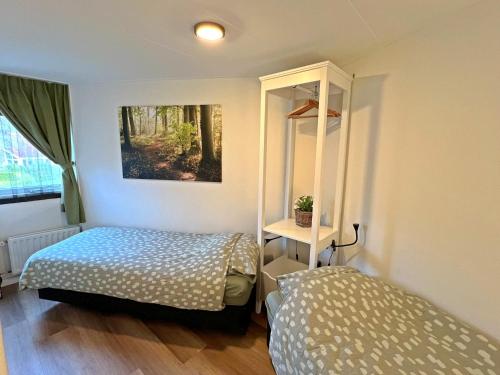 a small bedroom with a bed and a mirror at Vakantiewoning de Oeverzwaluw in hartje Drenthe in Zwiggelte