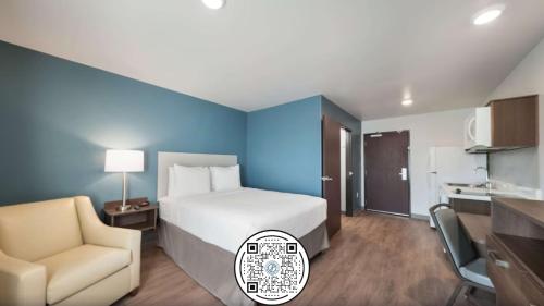 a hotel room with a bed and a chair at WoodSpring Suites Dallas Plano Central Legacy Drive in Plano