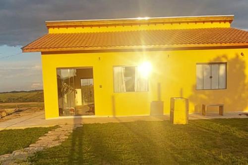 una casa amarilla con un cubo de basura delante de ella en Sítio Âmbar - Família, tranquilidade e privacidade, en Lambari