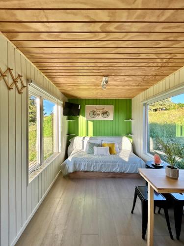 a bedroom with green walls and a bed and a table at Tinyhouses Mirador del Lago in Puerto Varas