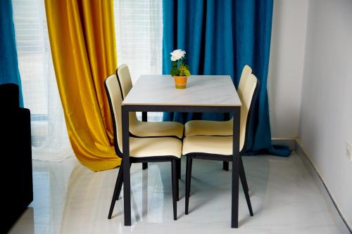 a table with two chairs and a vase with a flower on it at Modern Village Apartments in Chipata