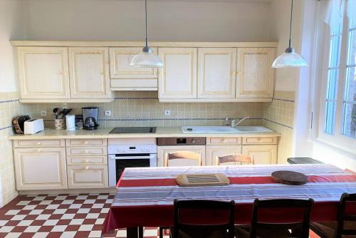 une cuisine avec des armoires blanches et une table avec des chaises dans l'établissement Maison bretonne avec BELLE VUE MER à TREGASTEL - Ref 50, à Trégastel