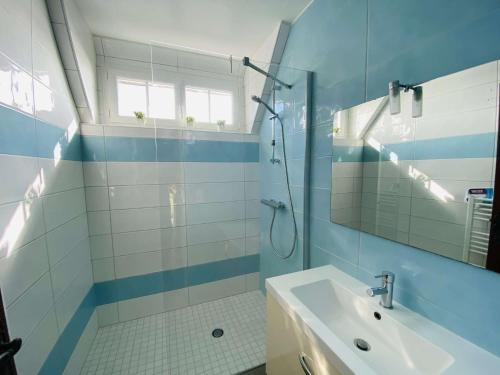 La salle de bains bleue et blanche est pourvue d'un lavabo et d'une douche. dans l'établissement Maison bretonne avec BELLE VUE MER à TREGASTEL - Ref 50, à Trégastel