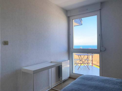 Cette chambre comprend un lit et une grande fenêtre. dans l'établissement Appartement VUE MER EXCEPTIONNELLE plage de Trestraou à PERROS-GUIREC - Réf 503, à Perros-Guirec