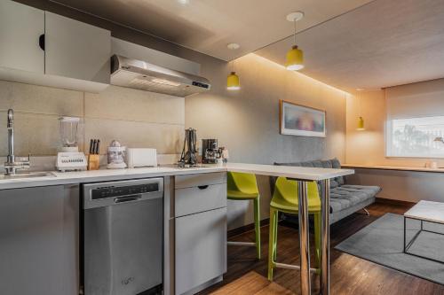 a kitchen with a counter and a table with yellow chairs at City Express Suites by Marriott Queretaro in Querétaro