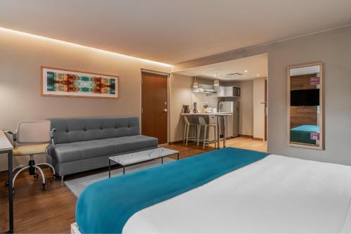 ケレタロにあるCity Express Suites by Marriott Queretaroのベッド1台、ソファ、キッチンが備わる客室です。