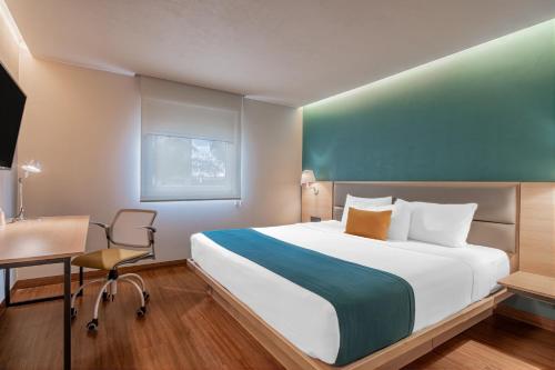 a bedroom with a bed and a desk and a chair at City Express Suites by Marriott Queretaro in Querétaro