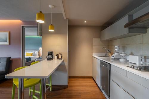 a kitchen with white countertops and yellow chairs at City Express Suites by Marriott Queretaro in Querétaro