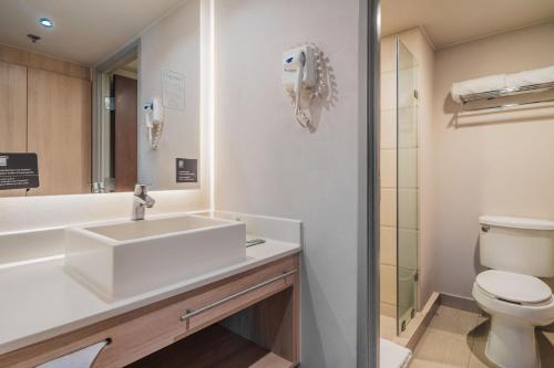 a bathroom with a sink and a toilet at City Express Suites by Marriott Queretaro in Querétaro