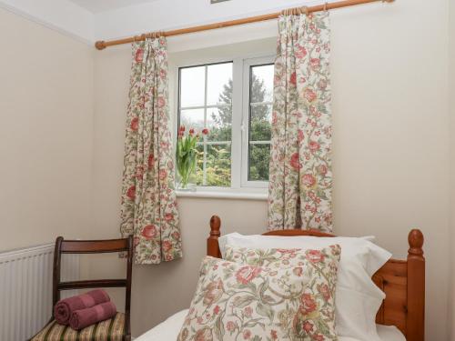 a bedroom with a bed and a window with curtains at Glebe Cottage in Yelverton