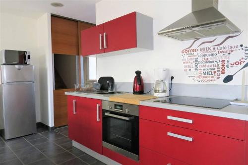 - une cuisine avec des placards rouges et une cuisinière dans l'établissement Jolie Maison Rénovée Exposée Sud avec Cour Fermée - ref 54, à Trégastel