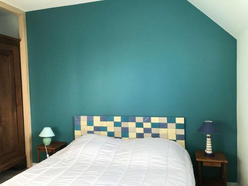 Schlafzimmer mit einem Bett mit blauer Wand in der Unterkunft Maison avec jardin, à 600m de la mer à TREGASTEL Réf - 57 in Trégastel