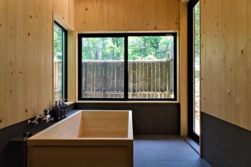 a bathroom with a large bath tub with a window at Noto cottage Hinoki no ie - Onsen in a cypress bathtub in Shika