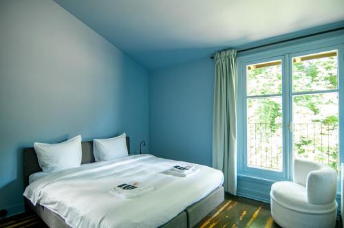 a blue room with a bed and a chair and a window at In het huis van Bello in Deventer