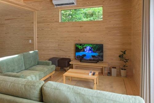 a living room with a couch and a tv at Noto cottage Hinoki no ie - Onsen in a cypress bathtub in Shika