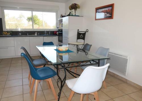 une cuisine avec une table et des chaises en verre dans l'établissement Maison récente avec jardin et terrasse exposées Sud à TREGASTEL - Réf 60, à Trégastel