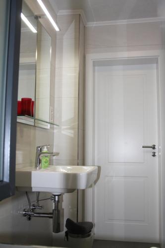 ein Badezimmer mit Waschbecken, Spiegel und Tür in der Unterkunft Fewo Lirich in Oberhausen