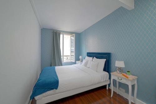 a blue bedroom with a bed and a window at Magnifique appartement à pied du château in Versailles