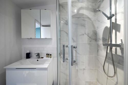 a white bathroom with a shower and a sink at Magnifique appartement à pied du château in Versailles