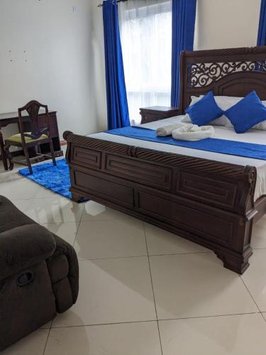 a bedroom with a large wooden bed with blue sheets at Gloria house in Syokimau