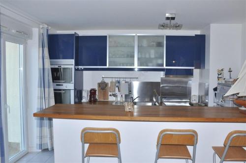 une cuisine avec des armoires bleues et un comptoir avec des chaises dans l'établissement Superbe appartement BELLE VUE MER à TREGASTEL - Réf 611, à Trégastel