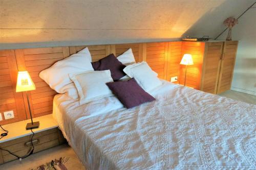 1 dormitorio con 1 cama con almohadas y 2 lámparas en Maisonnette de charme à 400m de la plage à TREGASTEL - Réf 64, en Trégastel