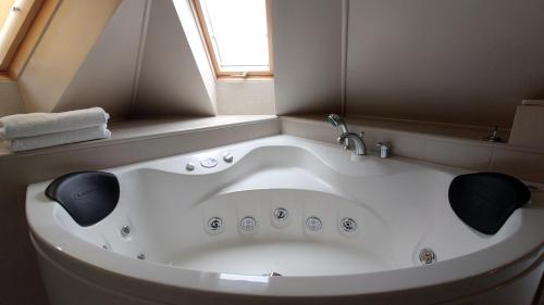 eine große weiße Badewanne im Bad mit Fenster in der Unterkunft Guesthouse Četri Vēji in Turkalne