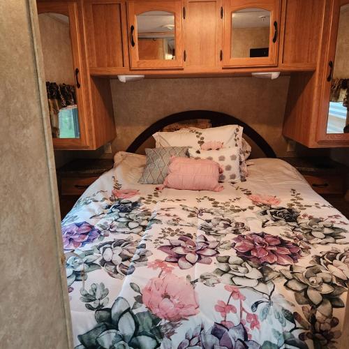 a bed with a floral comforter on it at Daisy Lake RV Campground in Nevis